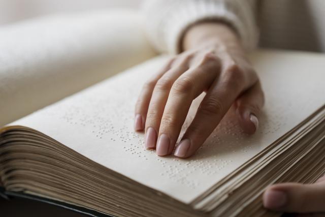 Une personne qui lit un livre en braille