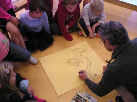 Philippe Mignon, entouré d'enfants, dessine un dragon 