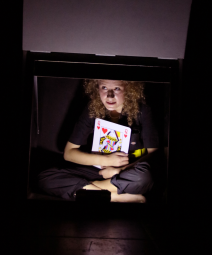 une petite fille frisée tenant dans ses mains une carte la dame de coeur